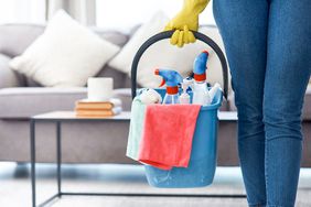 woman carrying cleaning bucket filled with supplies