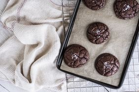 Chocolate cookies on a baking tray with wire cooling rack