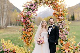 bride and groom smiling under ceremony floral archway