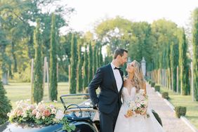 bride and groom looking at each other next to black vintage car