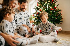 Family Opening Holiday Presents Wearing Matching Pajamas