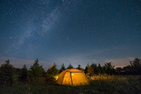 starry night sky over yellow camping tent