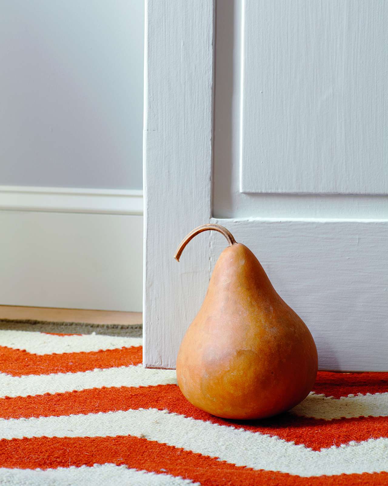 gourd placed door stopper on orange stripe carpet