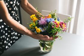 Woman arranging a bouquet of flowers in a glass vase
