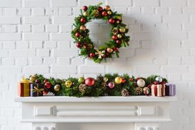 festive holiday wreath above fireplace decorated with garland and gift boxes