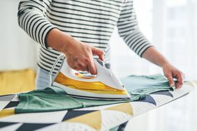 Woman ironing teal shirt with yellow clothing iron