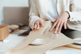 Craftswoman packing plate in wrapping paper for moving