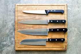 Kitchen knives set laying on wooden cutting board, flat lay, view from above