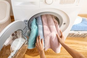 Woman pulling freshly cleaned towels out of drying machine