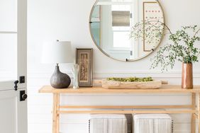 entryway with wooden table and circular mirror and plant