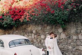 bride and groom share a kiss outside next to white vintage car