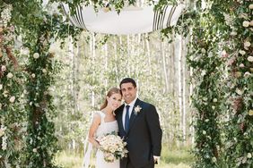 bride and groom beneath chuppah embellished with colorful flowers and greenery