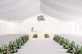 large white tent wedding ceremony space with white chairs and floral decor