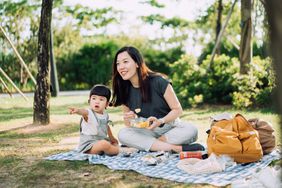 mother and young daughter enjoying picnic in park