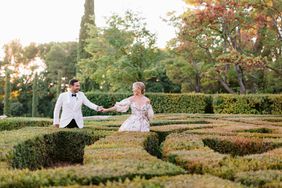 bride and groom holding hands walking through outdoor shrub garden
