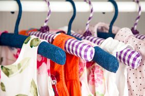 Baby closet with clothes hanging on purple hangers