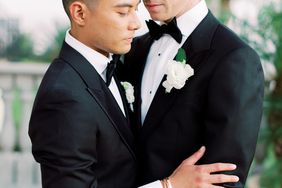 grooms embrace in their black tuxes