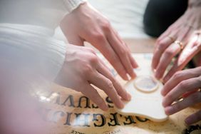 hands using ouija board