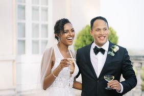 bride and groom smiling holding champagne coupe glasses